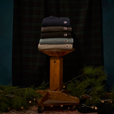 Stack of folded shirts on a wooden stand against a dark curtain background