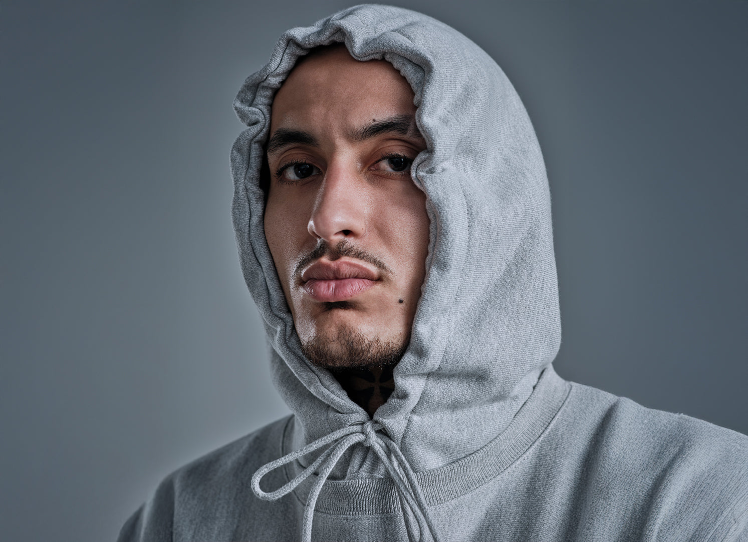 Man wearing a gray hoodie against a gray background