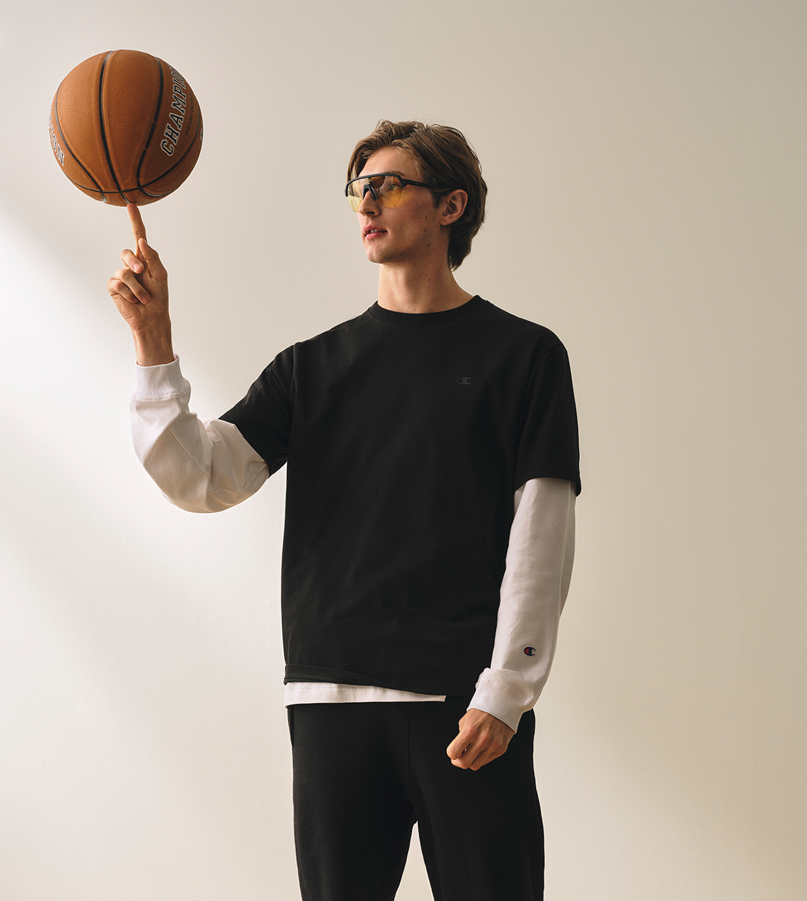 Man balancing a basketball on his finger against a plain background