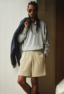 Person wearing a gray sweatshirt, beige shorts, and sunglasses indoors.