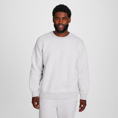 A man with short curly hair and a beard stands smiling in a Champion Powerblend Crewneck Sweatshirt, C Logo - Big & Tall, paired with matching sweatpants against a plain white background.