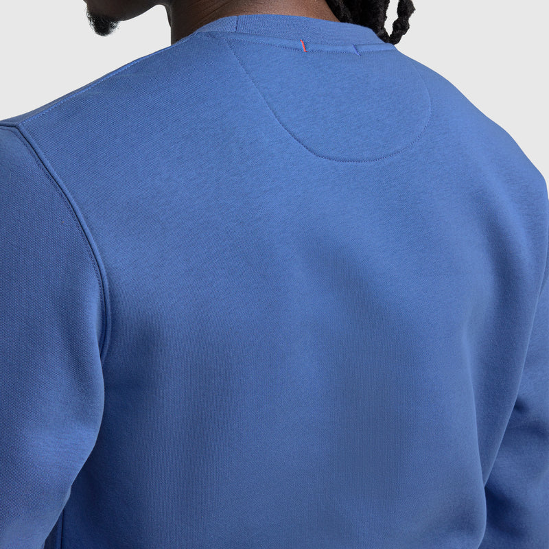 A person is shown from the back wearing the Champion Powerblend Crewneck Sweatshirt, C Logo. The image focuses on the upper back and shoulder area, highlighting the stitching and texture of this men's fleece pullover.