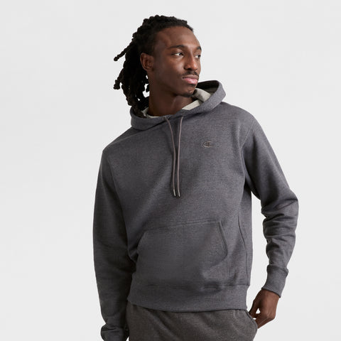 A man with long, dark dreadlocks models the Champion Powerblend Hoodie, C Logo, and matching pants against a plain light background as he looks to his left.
