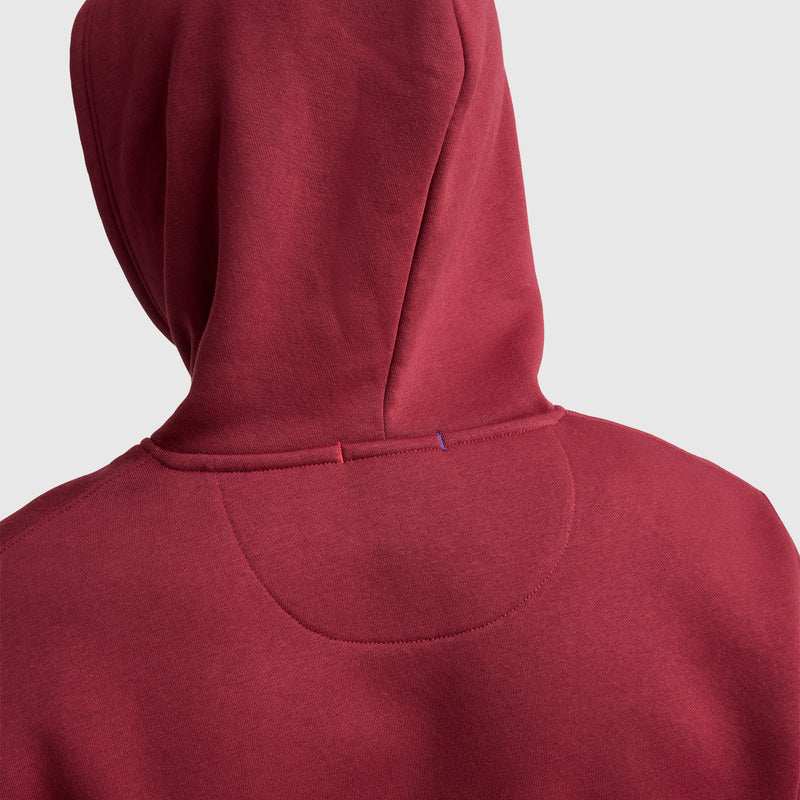 A close-up of the back of a person wearing the Champion Powerblend Hoodie, C Logo in maroon, with the hood up and visible stitching details, set against a plain light gray background.