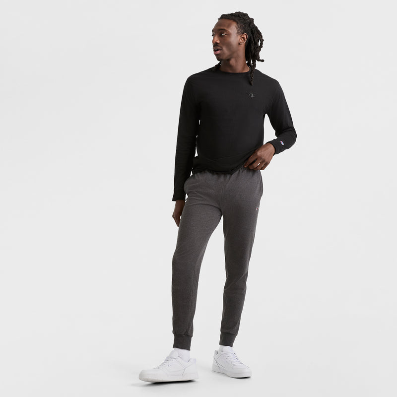 A man in a black shirt and Champion Lightweight Lounge Joggers with an elastic drawcord waistband and C Logo.