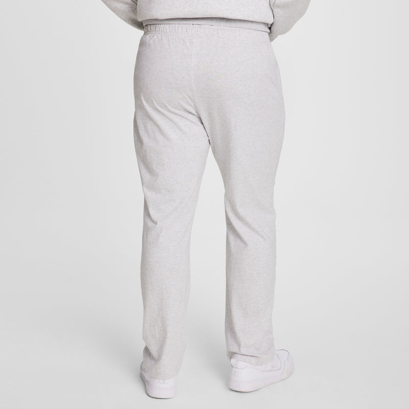Person wearing Champion Lightweight Lounge Pants, Open Hem, C Logo - Big & Tall in light gray, paired with white sneakers, shown from the back against a plain white background.