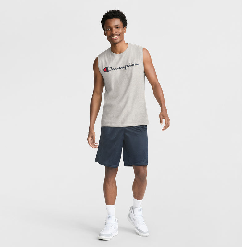 A smiling man in a sleeveless gray Champion shirt, Champion 9" Classic Mesh Shorts with C Logo in navy, white socks, and white sneakers stands against a plain white background.