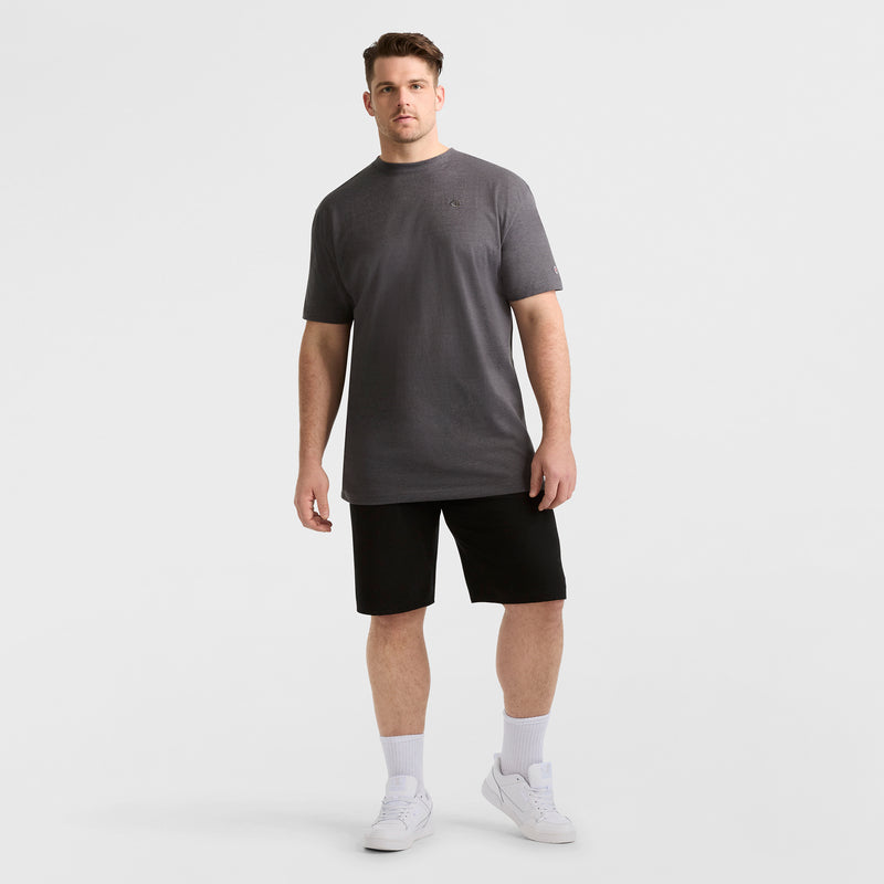 A man stands in a relaxed pose wearing dark gray t-shirt, Champion 9" Lightweight Lounge Shorts with C Patch Logo (Big & Tall), black in color, white crew socks, and white sneakers against a plain white background.