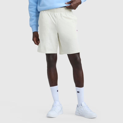 A person wears Champion's 9" Lightweight Lounge Shorts with C Patch Logo in light blue, paired with a matching sweatshirt, white crew socks, and white sneakers. Only the lower half is visible against a plain light background.