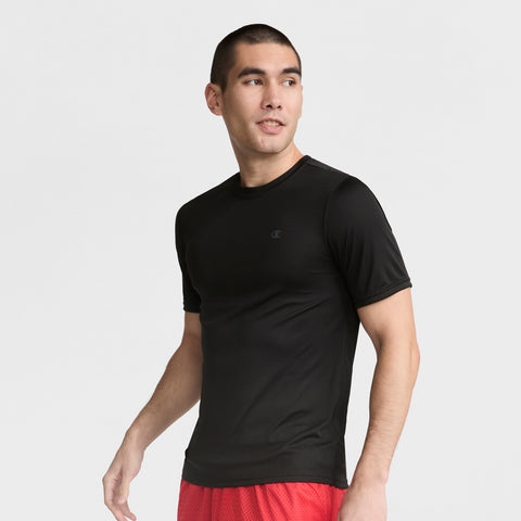 A man with short dark hair wears a fitted black Champion Sport T-Shirt with Reflective C Logo and red shorts, standing against a plain light background and looking to his left with a neutral expression.