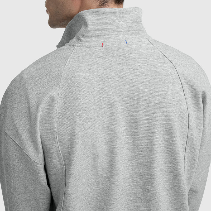 A person wears the Champion Gameday Full Zip Mock Neck, C Logo jacket, shown from the back with the collar up. Red and blue stitched lines near the top center of the collar accent its vintage athletic style.
