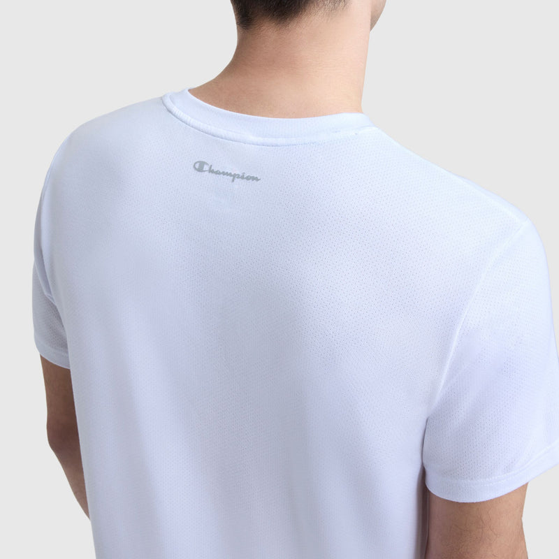 A person is seen from the back in a light blue Champion Sport Crewneck T-Shirt, Script Logo, featuring the logo near the neckline. The lightweight micro mesh fabric and a plain background give a fresh, athletic look.