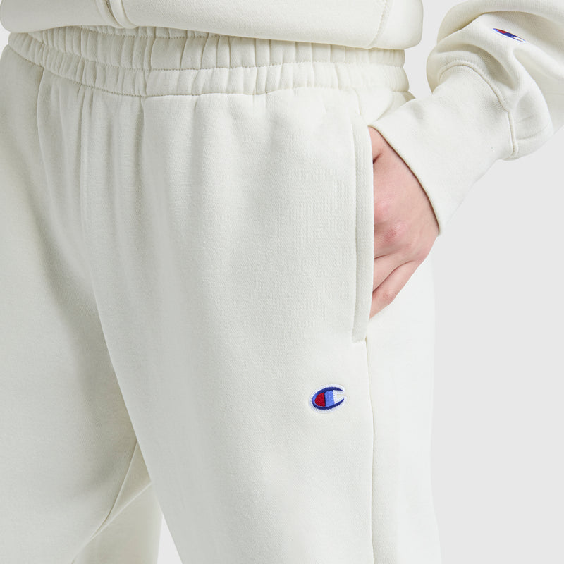 A person wearing Champion's Powerblend Oversized Sweatpants, C Logo, in cream with a matching sweatshirt and one hand in their pocket—comfortably styled women's loungewear ideal for relaxing days.
