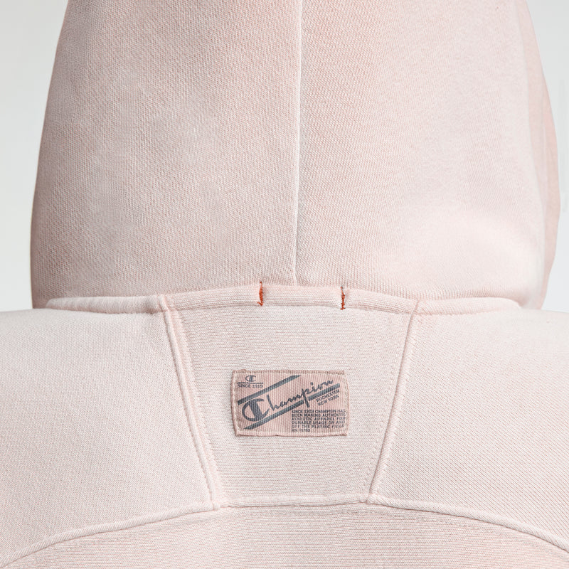 Close-up of the back of a light pink Champion Time Capsule Vintage 80's Full Zip Hoodie with the hood up, made from soft Reverse Weave fleece and featuring a stitched Champion patch near the neckline.