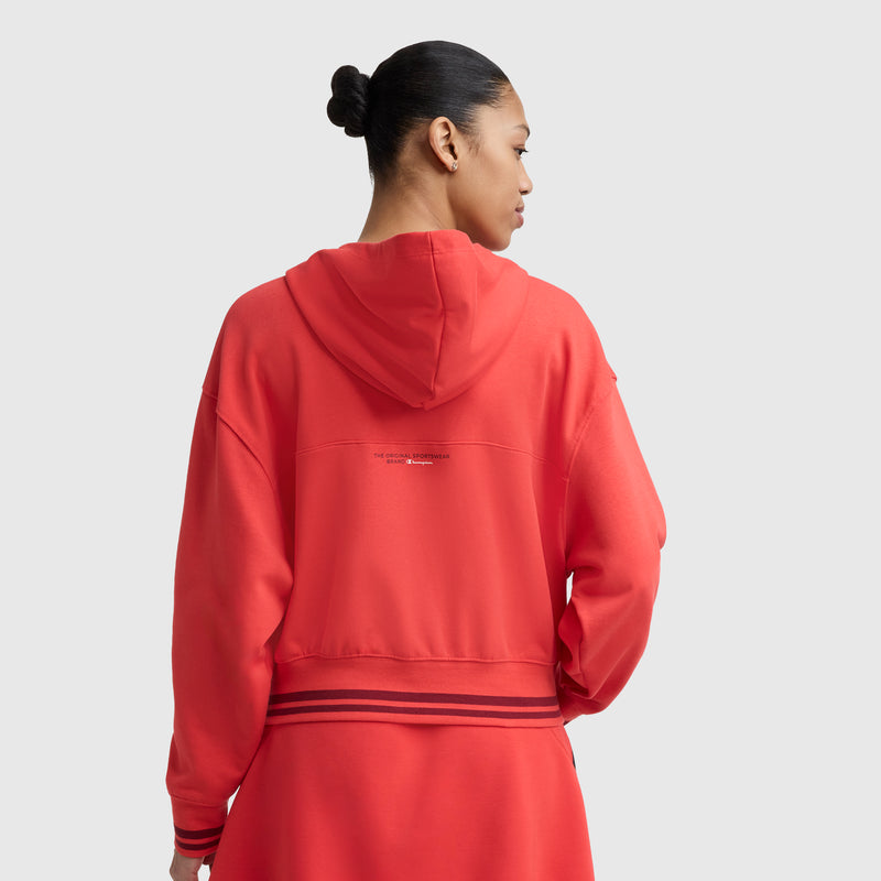 A person with dark hair in a bun, shown from the back against a plain light gray background, wears the Champion Tackle Lace Front Hoodie featuring a tonal embroidered C logo and black stripes near the bottom.