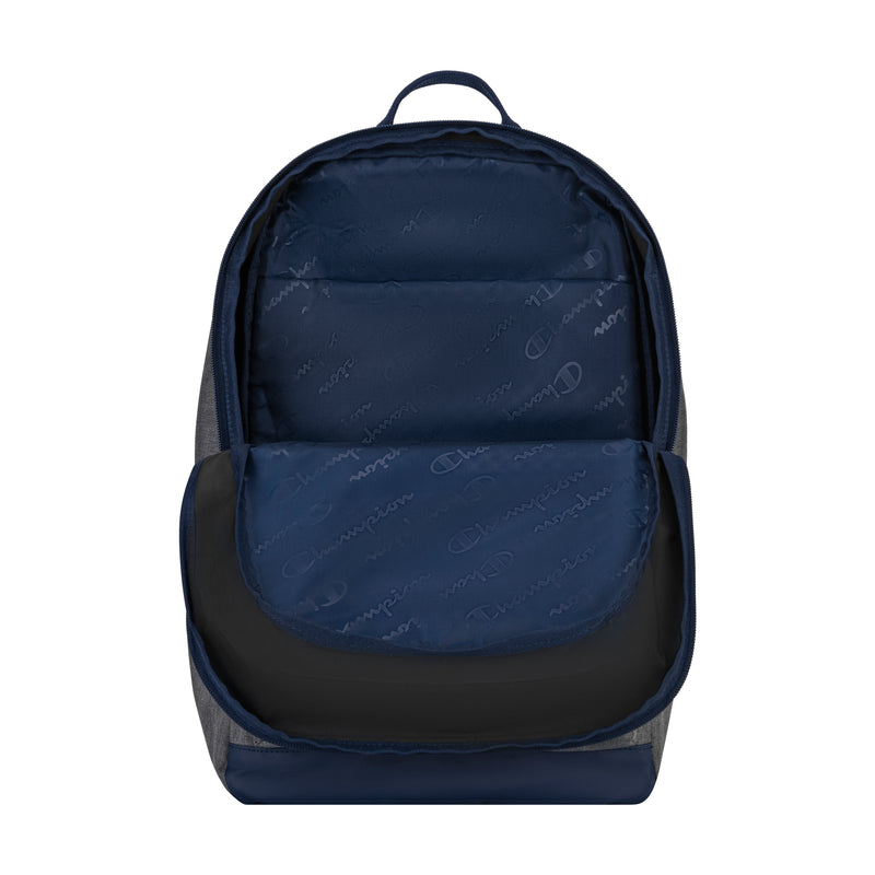 The Champion System Backpack in navy blue and gray is shown open, revealing several storage compartments, a padded laptop sleeve, and a front pocket—all lined with fabric featuring a subtle repeating Champion logo pattern.