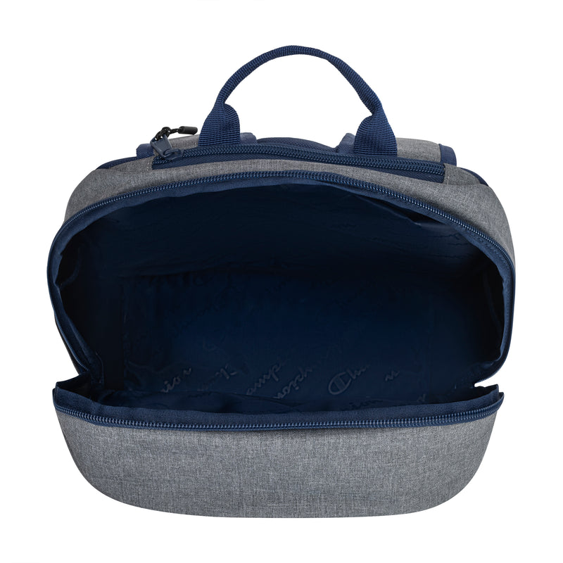 The Champion System Backpack is gray and navy blue, featuring multiple compartments, a padded laptop sleeve, a spacious main section with navy lining, and two top handles. The main compartment is shown unzipped and empty.