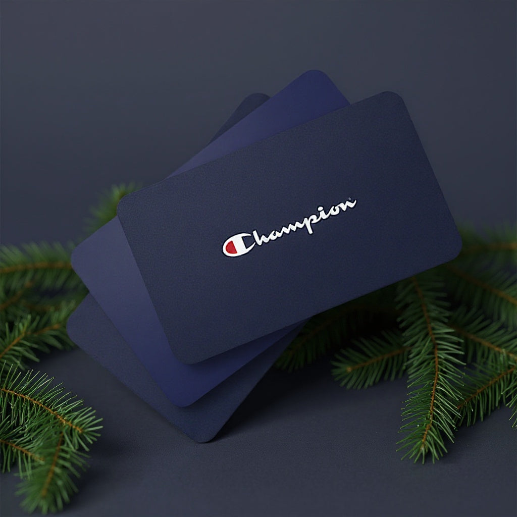 Navy blue gift cards with Champion logo on a dark background with greenery