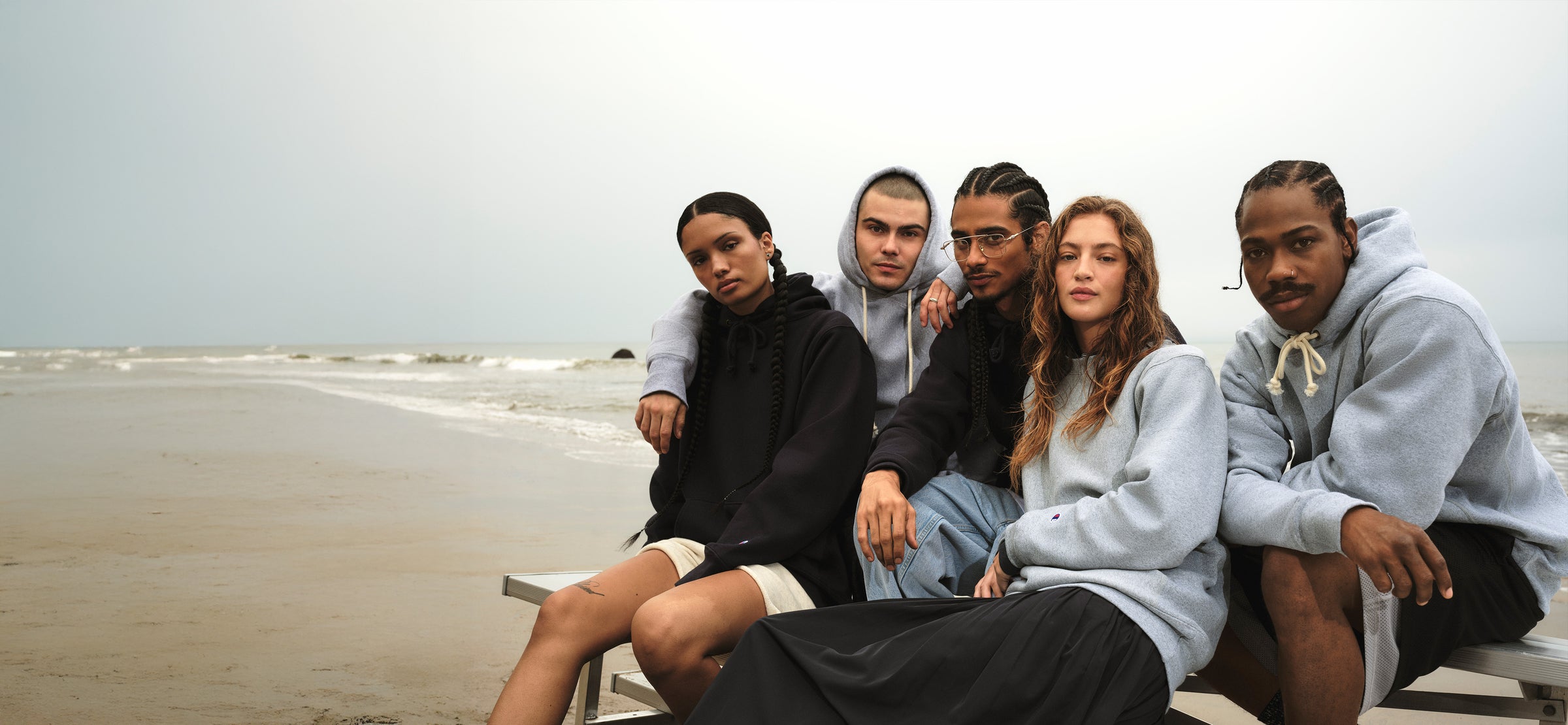 Five people sitting on a bench by the beach