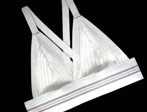 A white bralette with ribbed, triangular cups, double shoulder straps, and a white elastic band at the base featuring thin pink, gray, and black stripes, displayed on a black background.